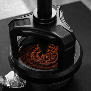 Precision Artisan Manual Coffee Grinder with stainless steel burrs and wooden handle next to coffee beans and brewed coffee