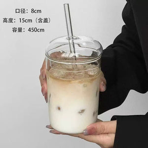 Glass straw cup with dome lid filled with iced coffee on white background