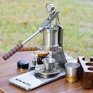Aleman 2S Hand Press espresso machine with polished stainless steel, wooden base, and PID temperature control on wooden countertop