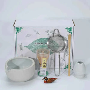 Japanese ceramic matcha tea set with bowl, whisk, sifter, and decorative items.