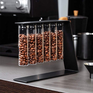 Magnetic coffee bean storage tubes with metal stand and stainless steel funnel on kitchen counter