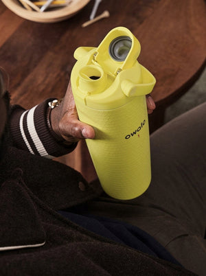 Hand holding the Lemon Yellow Owala golf bottle with the FreeSip lid open, seen from above
