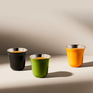 Black, green and orange stainless steel espresso cups on beige background