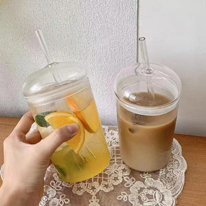 Glass straw cup with dome lid filled with iced coffee on white background