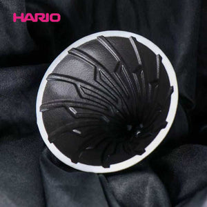 HARIO V60 Alpha ceramic coffee dripper with matte black finish and gold logo, showing integrated drip switch valve and ergonomic handle for hybrid immersion brewing.