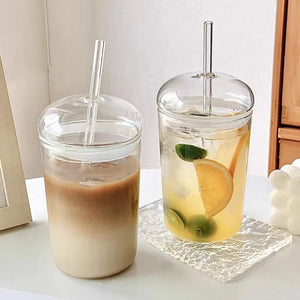 Glass straw cup with dome lid filled with iced coffee on table