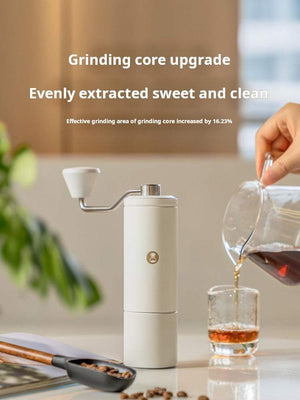 Manual coffee grinder with stainless steel burr and ergonomic crank handle on white background