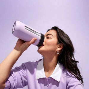 Person drinking from purple insulated travel mug