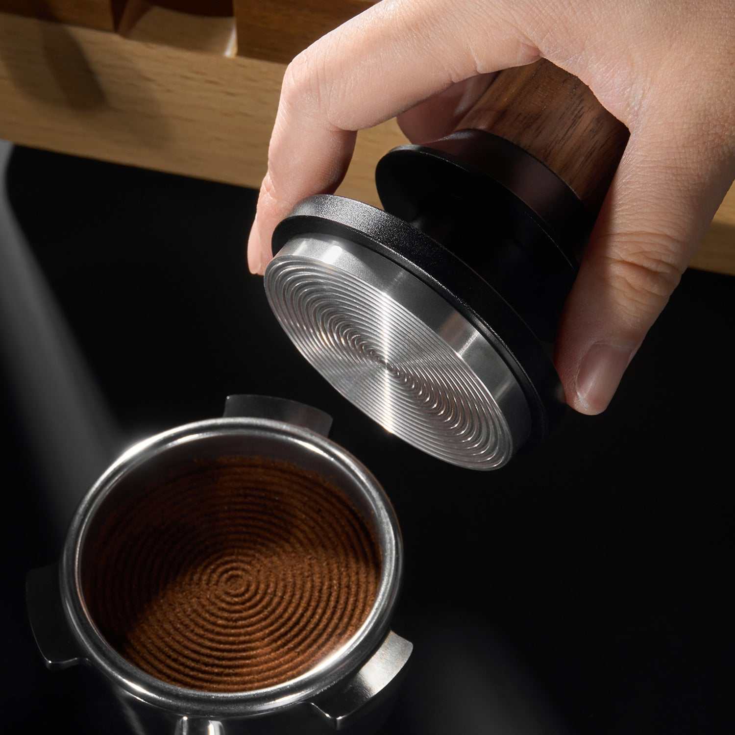 Espresso tamper with natural wood handle and ripple stainless steel base for even coffee extraction