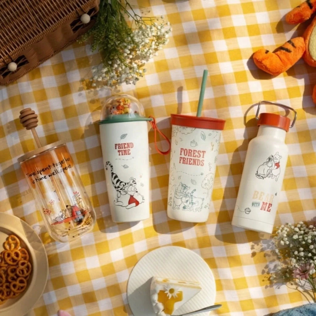 Four Winnie the Pooh drinkware items on yellow gingham cloth