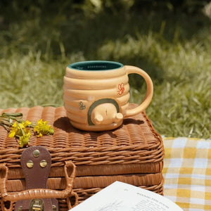 Winnie the Pooh beehive mug in cream and green on picnic basket
