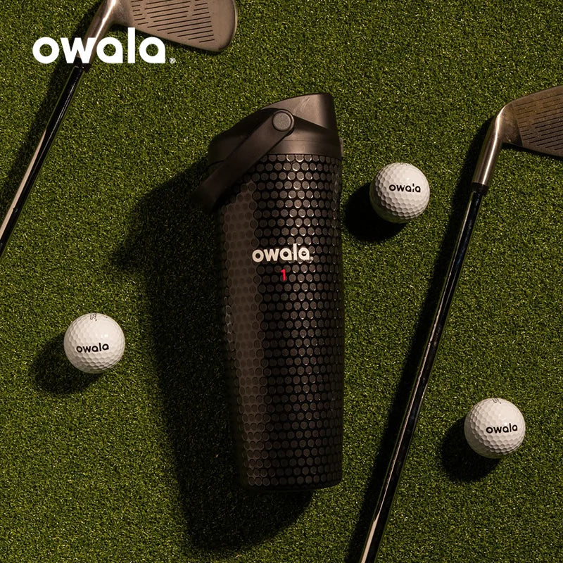Owala Out of Bounds golf bottle on grass with golf clubs and golf balls