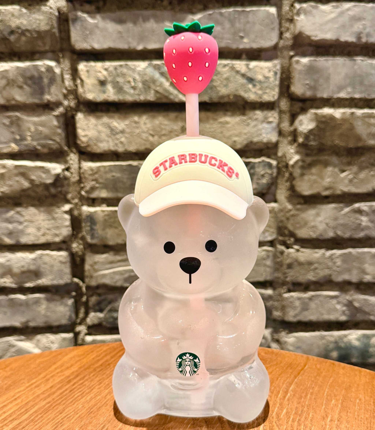 A close-up thumbnail of the starbucks bear cup 2026 pink against a brick wall, capturing the design of كوب ستاربكس الدبدوب الوردي 2026 آخر اصدار.