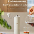 Manual coffee grinder with stainless steel burr and ergonomic crank handle on white background