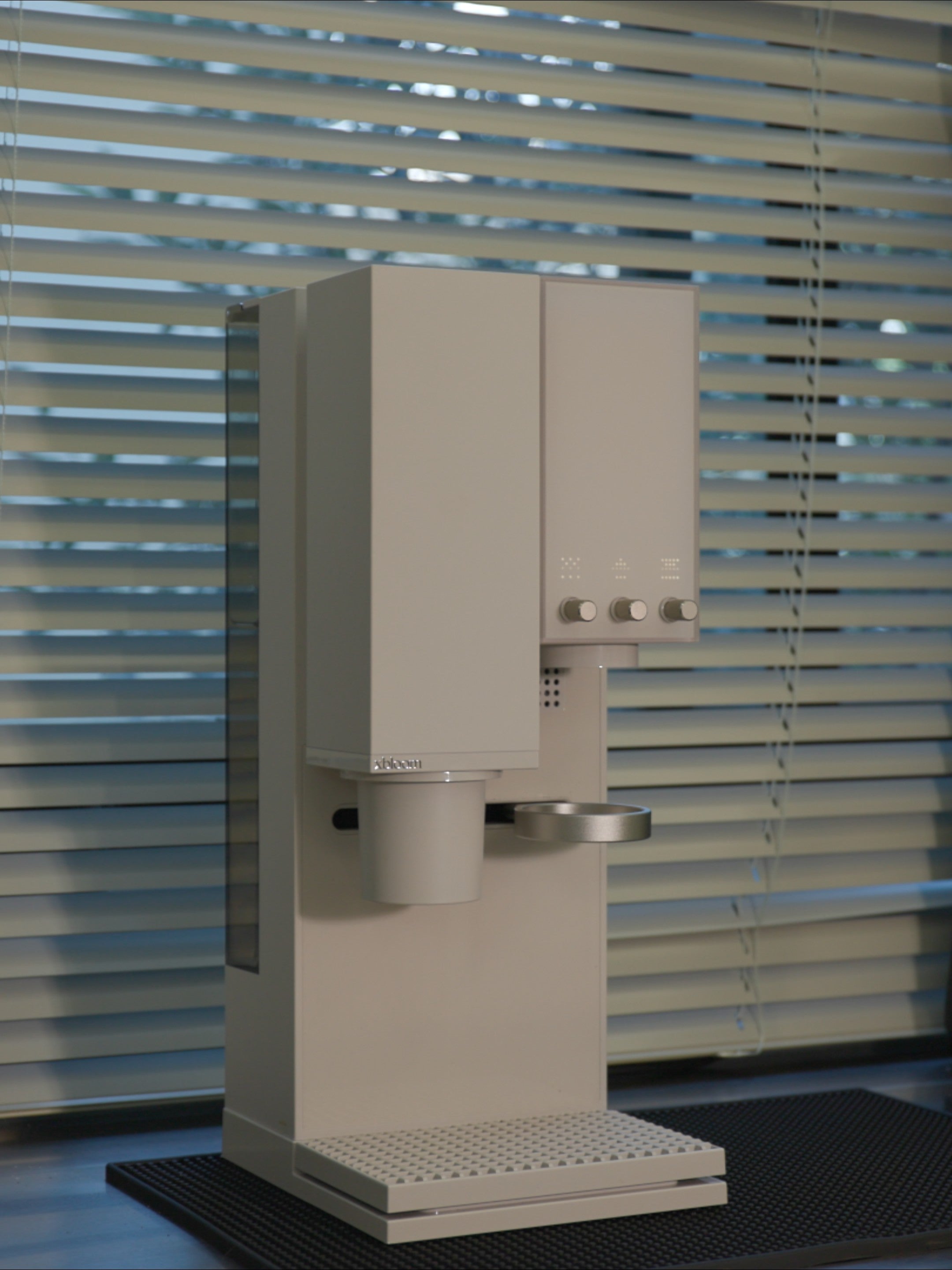 xBloom Studio white smart brewer in a natural light setting near a window.